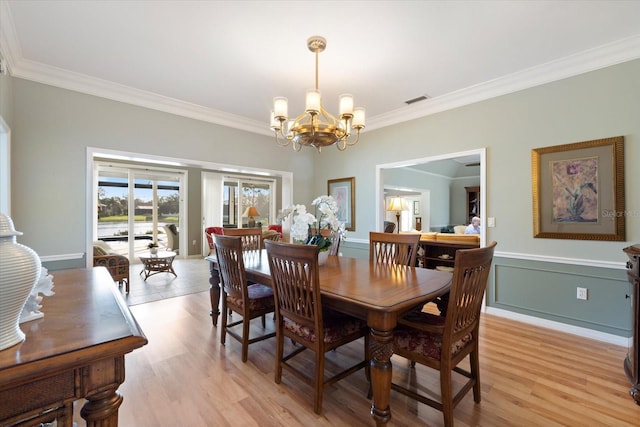 dining space featuring a notable chandelier, crown molding, and light wood-type flooring