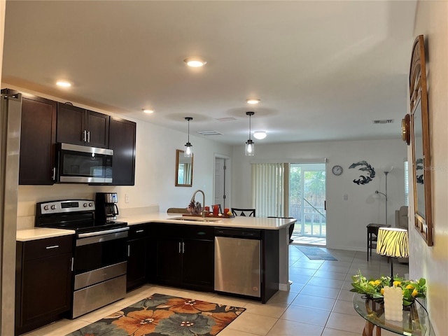 kitchen with light tile patterned flooring, sink, decorative light fixtures, appliances with stainless steel finishes, and kitchen peninsula