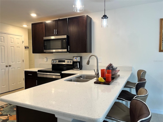 kitchen featuring appliances with stainless steel finishes, sink, a kitchen bar, hanging light fixtures, and kitchen peninsula