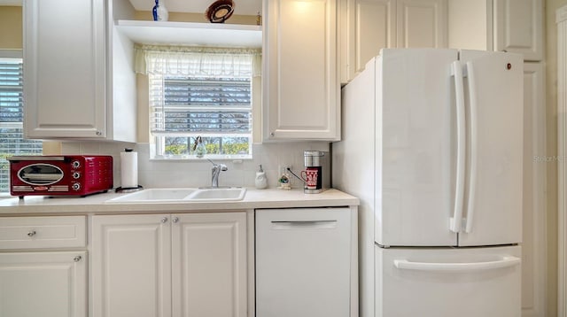 7649 Quinto Dr, Sarasota, FL 34238 - kitchen with decorative backsplash, a sink, white cabinets, and white appliances
