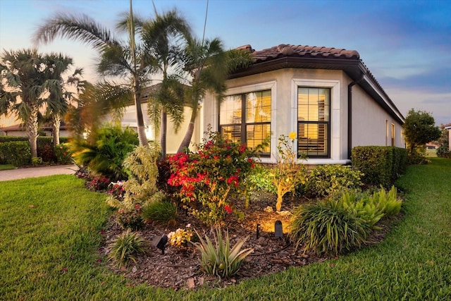 property exterior at dusk with a lawn