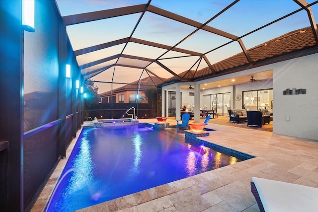 pool at dusk featuring ceiling fan, a lanai, pool water feature, and a patio area