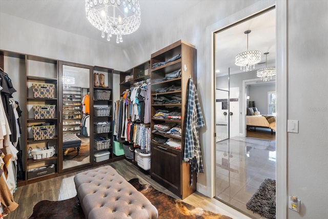 walk in closet featuring wood-type flooring and an inviting chandelier