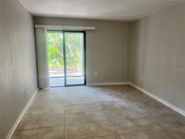 empty room featuring baseboards and light tile patterned floors