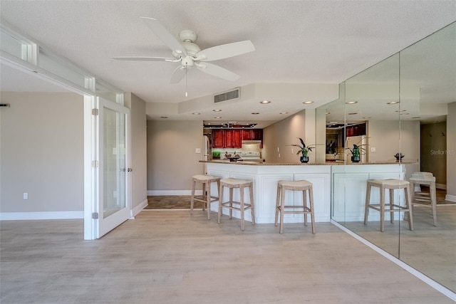 kitchen with freestanding refrigerator, visible vents, a textured ceiling, and a kitchen breakfast bar