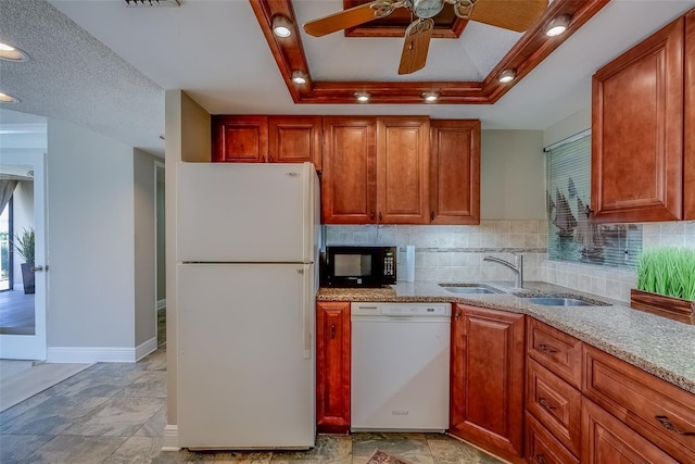 kitchen with white appliances, a tray ceiling, decorative backsplash, and a sink