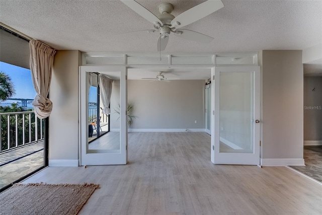 empty room featuring a textured ceiling, wood finished floors, and baseboards