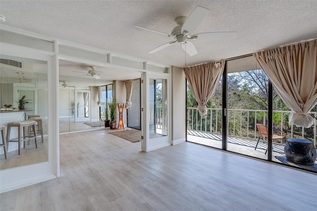 interior space with a textured ceiling, floor to ceiling windows, visible vents, and wood finished floors