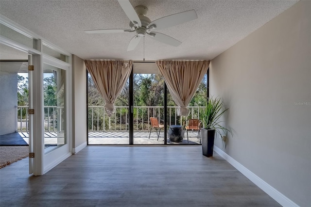 entryway with expansive windows, wood finished floors, and baseboards