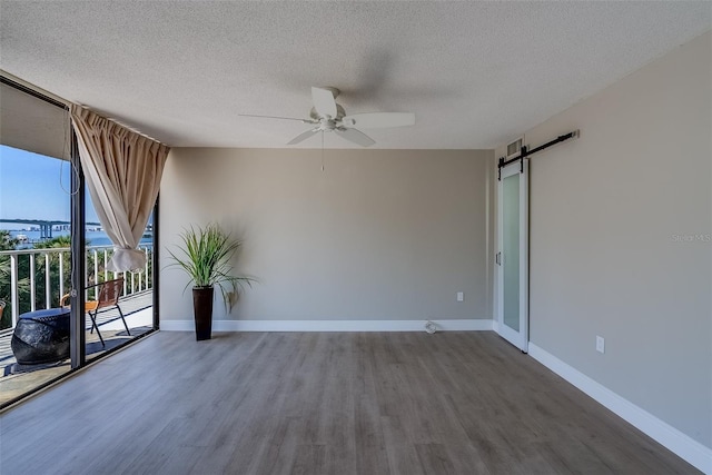 spare room featuring a wall of windows, wood finished floors, baseboards, and a barn door