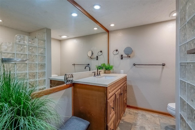 bathroom featuring toilet, recessed lighting, vanity, baseboards, and walk in shower