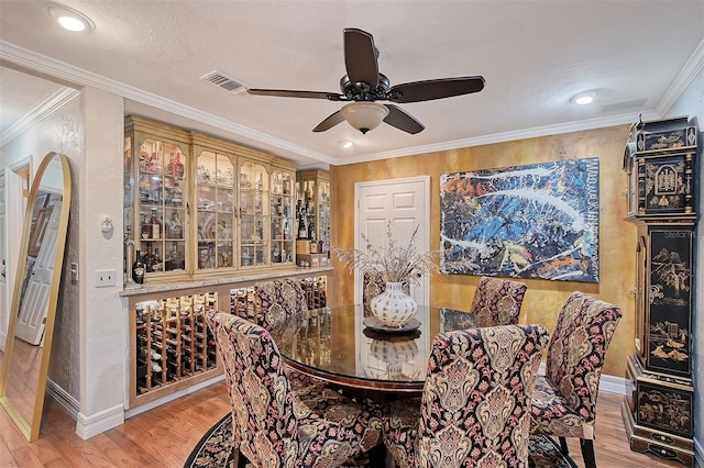 dining room with visible vents, baseboards, ceiling fan, ornamental molding, and light wood-type flooring