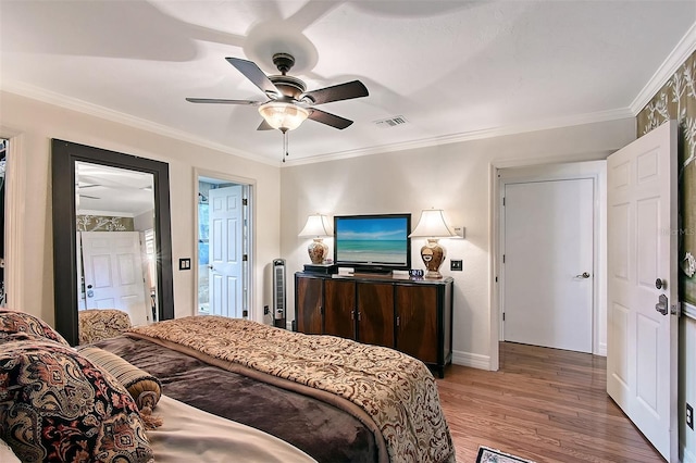 bedroom with ornamental molding, wood finished floors, visible vents, and a ceiling fan