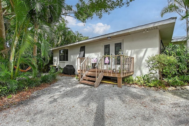 view of front of house featuring french doors, a deck, and stucco siding