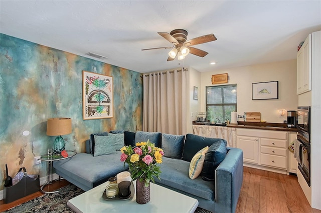 living room featuring recessed lighting, visible vents, an accent wall, ceiling fan, and wood finished floors