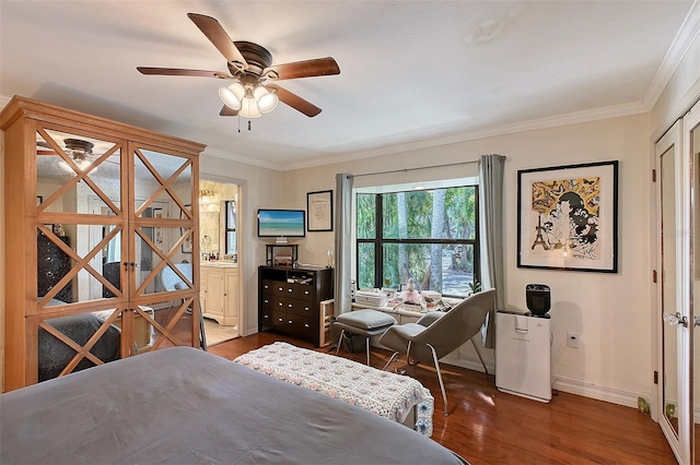 bedroom with dark wood-style floors, crown molding, ensuite bathroom, a ceiling fan, and baseboards