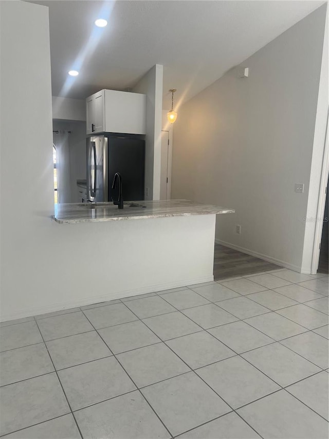 kitchen featuring white cabinetry, stainless steel refrigerator, and kitchen peninsula