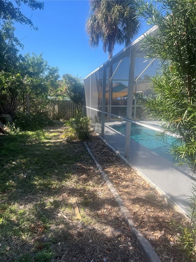 view of side of home featuring glass enclosure and a fenced in pool