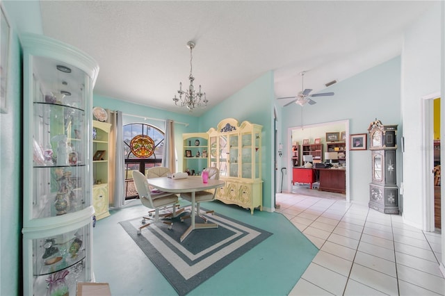 dining space featuring vaulted ceiling, ceiling fan with notable chandelier, light tile patterned flooring, and a textured ceiling