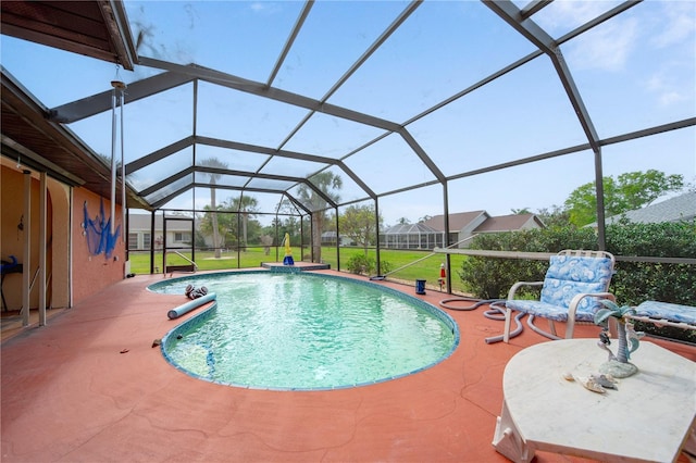 view of pool with a patio area, a lawn, and glass enclosure