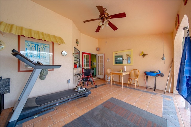 exercise area featuring ceiling fan, lofted ceiling, and tile patterned flooring