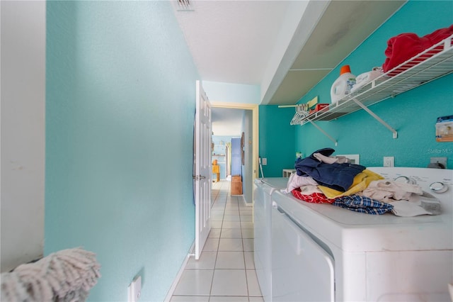 clothes washing area with light tile patterned flooring and washer and clothes dryer