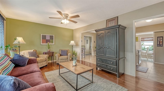 living room with a ceiling fan, wood finished floors, and wainscoting