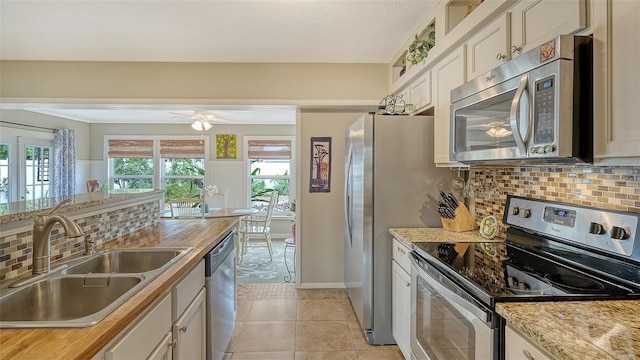 kitchen with a wealth of natural light, appliances with stainless steel finishes, a sink, and light tile patterned flooring