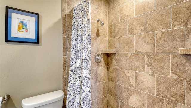 full bath featuring tiled shower and toilet