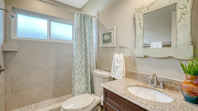 bathroom featuring a tile shower, vanity, and toilet