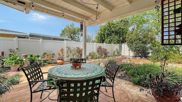 view of patio featuring outdoor dining area, a fenced backyard, an outdoor structure, and a shed