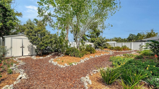 view of yard featuring fence, a storage unit, and an outbuilding