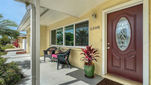 doorway to property featuring covered porch and stucco siding