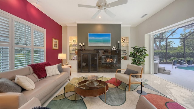 living room featuring built in features, crown molding, visible vents, a premium fireplace, and ceiling fan