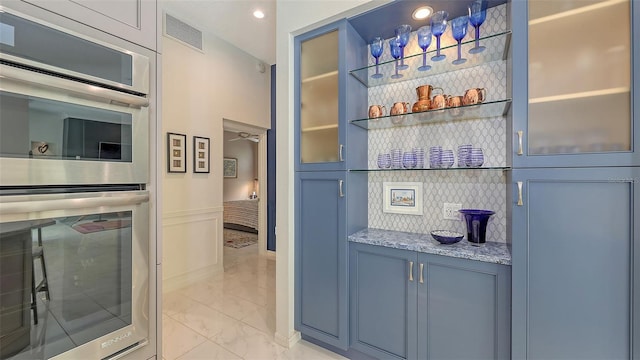 bar featuring marble finish floor, double oven, tasteful backsplash, and visible vents