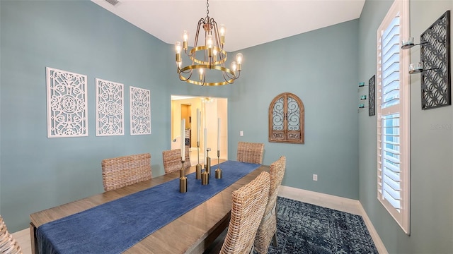 dining room featuring a chandelier, baseboards, plenty of natural light, and a high ceiling