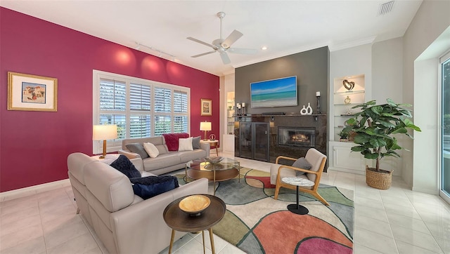 living area with light tile patterned flooring, visible vents, built in features, and a glass covered fireplace