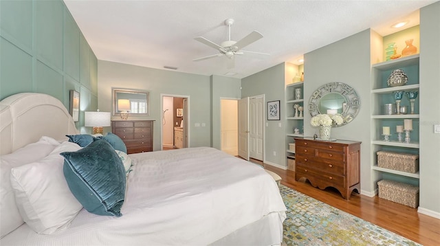 bedroom featuring visible vents, connected bathroom, baseboards, and wood finished floors