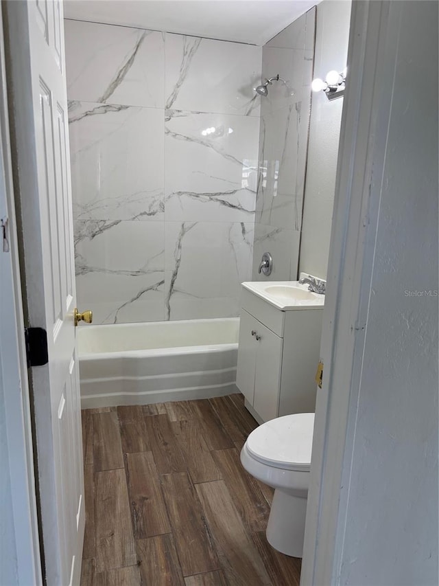 full bathroom featuring hardwood / wood-style flooring, tiled shower / bath, vanity, and toilet