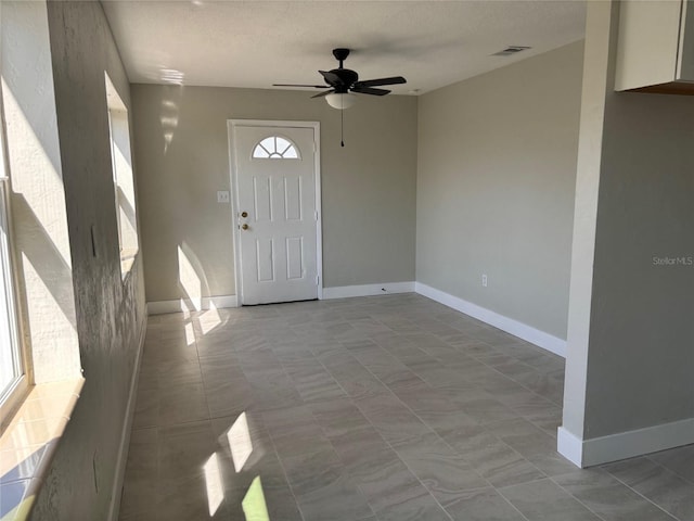 foyer entrance with a textured ceiling and ceiling fan