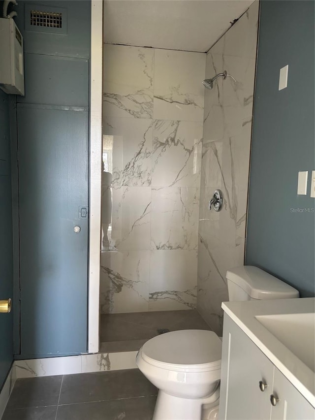 bathroom with vanity, a tile shower, and toilet