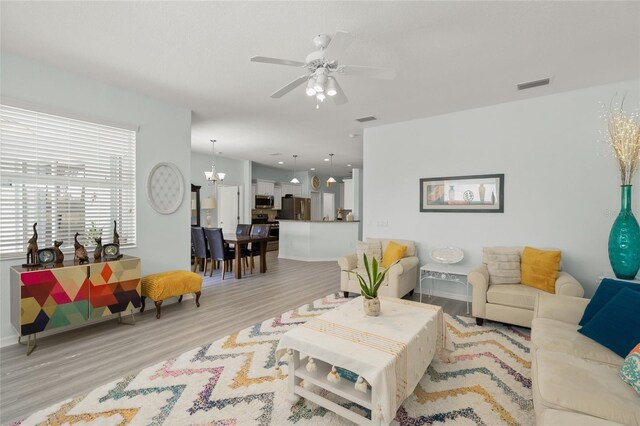 8956 Stone Harbour Loop, Bradenton, FL 34212 - living room with visible vents, light wood finished floors, ceiling fan with notable chandelier, and baseboards