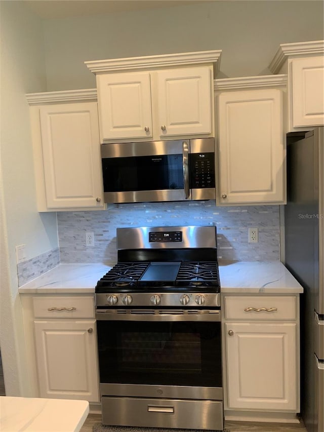 8956 Stone Harbour Loop, Bradenton, FL 34212 - kitchen with stainless steel appliances, white cabinetry, and tasteful backsplash