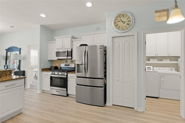 8956 Stone Harbour Loop, Bradenton, FL 34212 - kitchen with light wood finished floors, stainless steel appliances, white cabinetry, visible vents, and washing machine and dryer