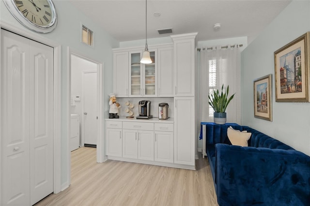 8956 Stone Harbour Loop, Bradenton, FL 34212 - interior space with visible vents, glass insert cabinets, and light wood-style flooring