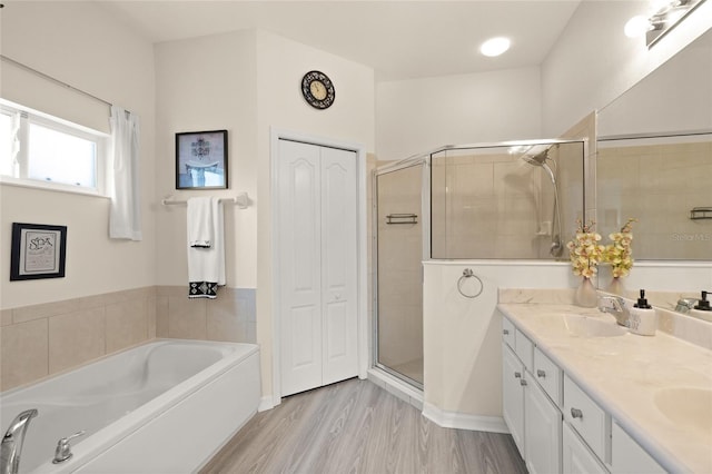 8956 Stone Harbour Loop, Bradenton, FL 34212 - bathroom featuring a sink, double vanity, wood finished floors, a garden tub, and a stall shower