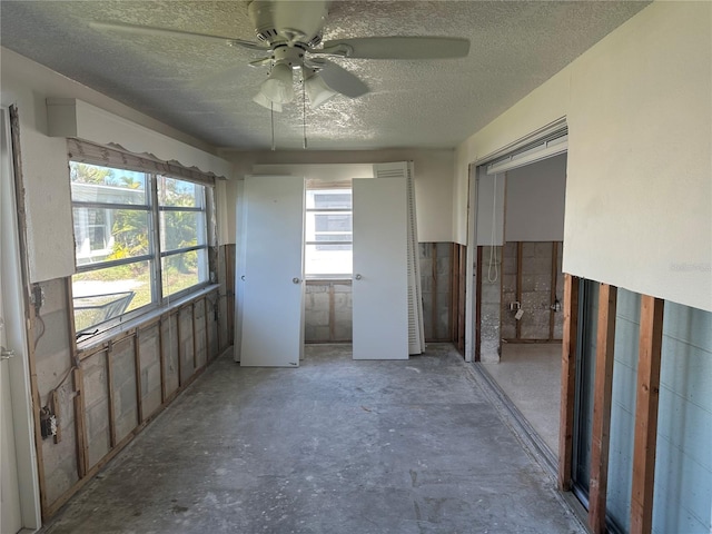 empty room with unfinished concrete flooring, a textured ceiling, and ceiling fan