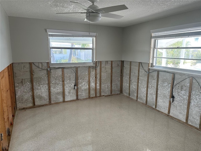 spare room featuring a textured ceiling, a ceiling fan, and a healthy amount of sunlight