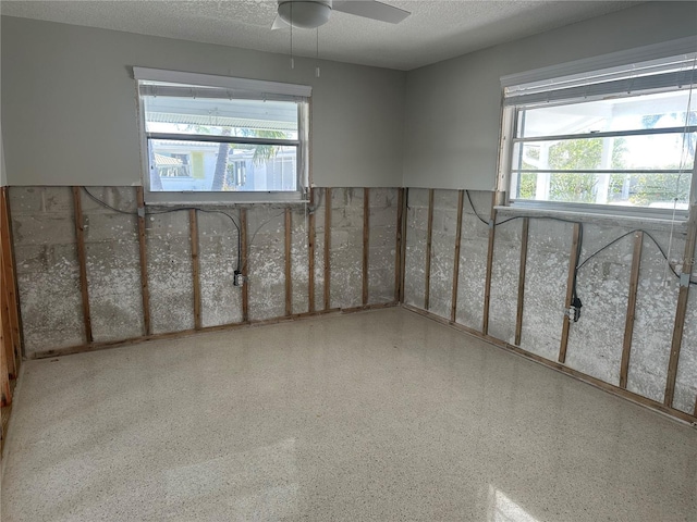 unfurnished room with a textured ceiling, ceiling fan, and speckled floor