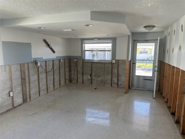 basement with a textured ceiling and wainscoting